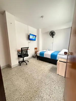 a bedroom with a bed and a desk and a television at Roomies House By Rincon in Medellín