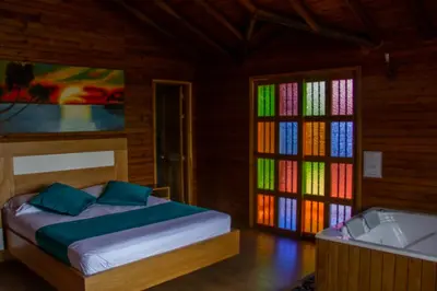 a bedroom with a bed and a tub and windows at Sotavento Cabañas in Guatapé