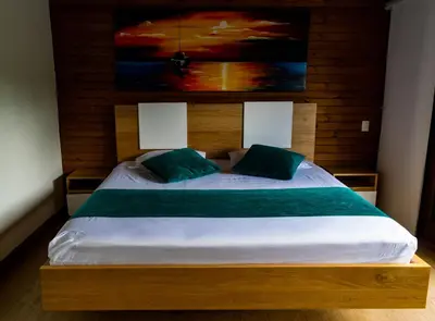 a bedroom with a large wooden bed with green pillows at Sotavento Cabañas in Guatapé