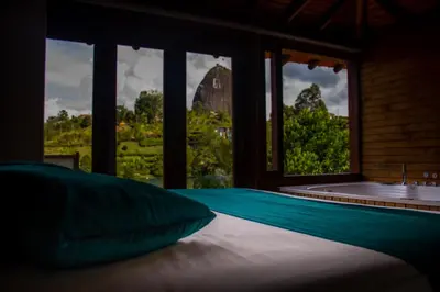 a bedroom with a bath tub and a bed with a window at Sotavento Cabañas in Guatapé
