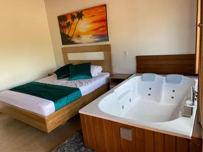 a bedroom with a bed and a bath tub at Sotavento Cabañas in Guatapé
