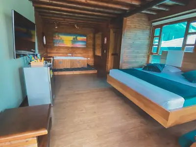 a bedroom with a large bed and a tub at Sotavento Cabañas in Guatapé
