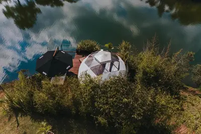 a couple of umbrellas and a boat in the water at Domus Glamping Guatapé in Guatapé