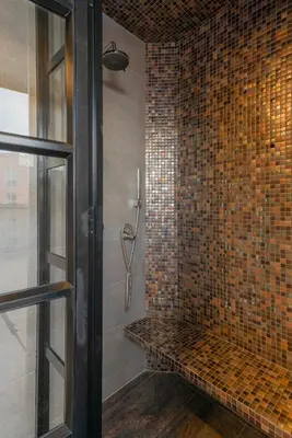 a bathroom with a shower with mosaic tiles on the wall at VPV Suites in Medellín