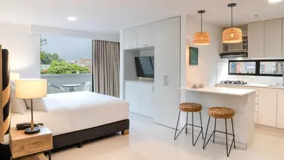 a bedroom with a bed and a kitchen with a counter at Origen Local Suites in Medellín