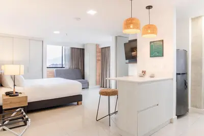 a hotel room with a bed and a kitchen at Origen Local Suites in Medellín