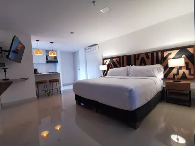 a bedroom with a large bed and a kitchen at Origen Local Suites in Medellín