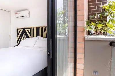 a bedroom with a bed and a window with plants at Origen Local Suites in Medellín