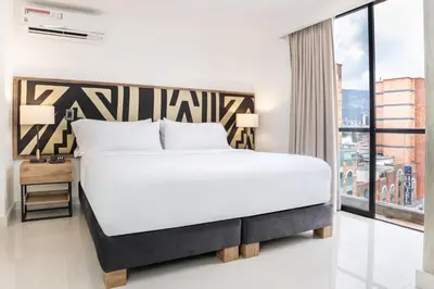 a bedroom with a large bed and a large window at Origen Local Suites in Medellín