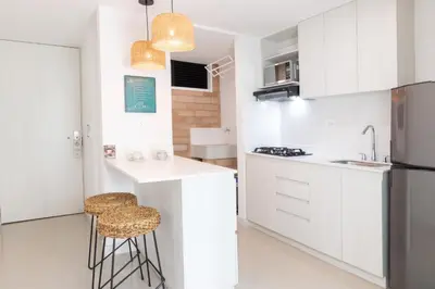 a kitchen with white cabinets and stools in it at Origen Local Suites in Medellín