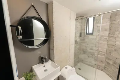 a bathroom with a shower and a sink and a mirror at The Coffee Club Apartahotel in Manizales