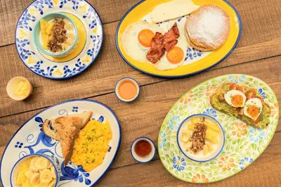 four plates of breakfast food on a wooden table at Masaya Medellin in Medellín