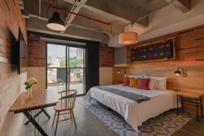 a bedroom with a bed and a table and a desk at Masaya Medellin in Medellín