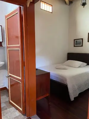 a small bedroom with a bed and a door at Casa Patrimonial Abejorral - CASA GASAMA in Abejorral