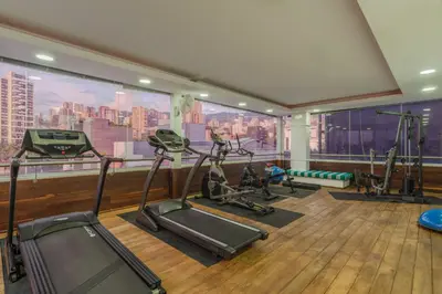a gym with tread machines and a large window at Hotel Du Parc in Medellín