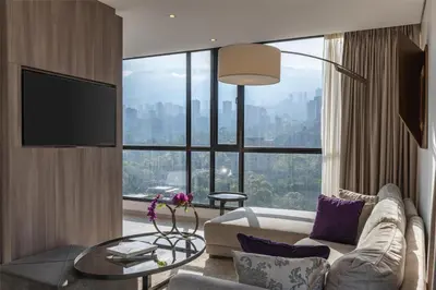 a living room with a couch and a large window at York Medellin, Curio Collection by Hilton in Medellín