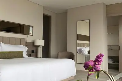 a bedroom with a large white bed and a mirror at York Medellin, Curio Collection by Hilton in Medellín