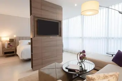a living room with a couch and a tv and a bed at York Medellin, Curio Collection by Hilton in Medellín
