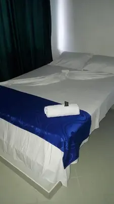 a white bed with a blue blanket on it at HOTEL BRISAS DE SANTA FE in Santa Fe de Antioquia