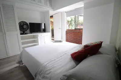 a bedroom with a large white bed and a television at Alojamiento en apartamento cerca a Provenza - M203 By Roots Rentals in Medellín