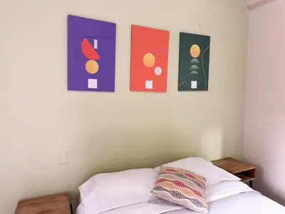 a bedroom with a bed with four paintings on the wall at Alojamiento en apartamento cerca a Provenza - M203 By Roots Rentals in Medellín
