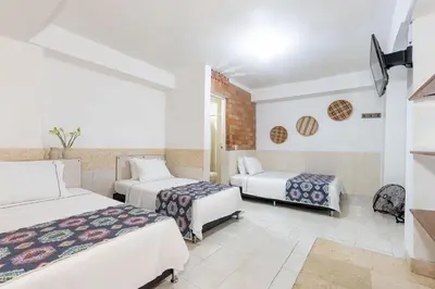 a hotel room with two beds and two tables at Gran Caribe Hotel in Medellín