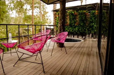 three pink chairs and a table on a deck at Mumu by Bernalo Hotels in Guatapé