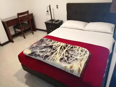 a bedroom with a bed and a chair and a desk at HOTEL MI CASA DEL NORTE in Santa Rosa de Osos