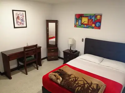 a bedroom with a bed and a desk and a mirror at HOTEL MI CASA DEL NORTE in Santa Rosa de Osos