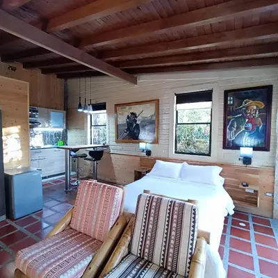 a bedroom with a bed and two chairs at CABAÑAS MONTEVERDE - Guarne ANT in Guarne