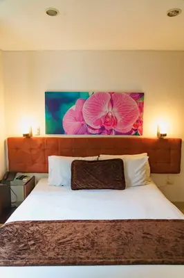 a bedroom with a bed with a flower painting on the wall at Hotel Boutique las Rosas 5 G in Medellín