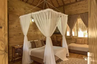 a bedroom with two beds with curtains in a cabin at La Ardilla de Santa Fe by Bernalo Hotels in Santa Fe de Antioquia