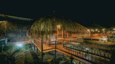 a resort building with a thatched roof at night at La Ardilla de Santa Fe by Bernalo Hotels in Santa Fe de Antioquia