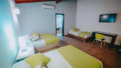 a hotel room with two beds and a tv at La Ardilla de Santa Fe by Bernalo Hotels in Santa Fe de Antioquia