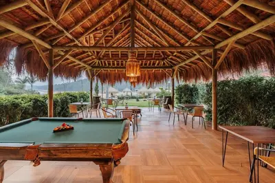 a pool table in a restaurant with a thatched roof at Pietrasanta hotel campestre frente a la represa del Peñol y Guatape in Guatapé