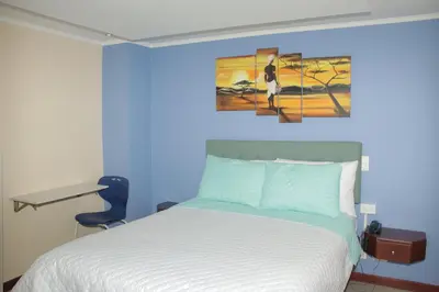 a blue bedroom with a bed and a painting on the wall at Hotel Dubai in Manizales