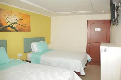 a bedroom with two beds and a painting on the wall at Hotel Dubai in Manizales