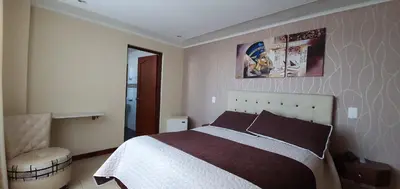 a bedroom with a bed and a chair at Hotel Dubai in Manizales