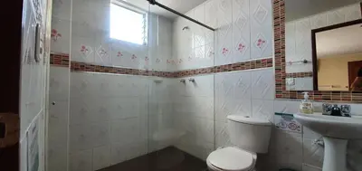a white bathroom with a toilet and a sink at Hotel Dubai in Manizales