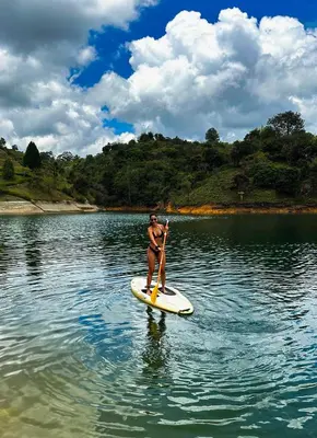 a woman in a bikini on a paddle board in the water at The Boato Hotel in Guatapé