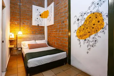 a small room with a bed and a brick wall at Botánica Casa Hotel in Medellín
