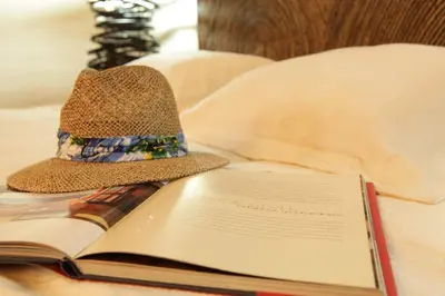 a hat and an open book on a bed at Hotel y Spa Santa Fe Colonial in Santa Fe de Antioquia
