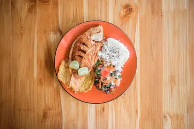 a red plate of food on a wooden table at La Perla Negra - Black Pearl Eco Hostel in San Rafael