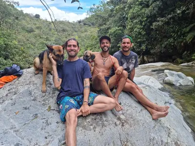 three men sitting on a rock with their dogs at La Perla Negra - Black Pearl Eco Hostel in San Rafael