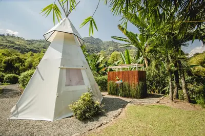 a small white teepee tent in a garden at Cerro Tusa Glamping in Titiribí
