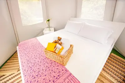 a white bed with a basket with a teddy bear on it at Cerro Tusa Glamping in Titiribí