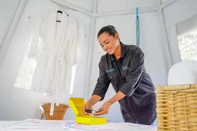 a woman standing at a table with a yellow box at Cerro Tusa Glamping in Titiribí