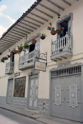 a white building with two balconies and two doors at La Estancia Hotel Boutique in Salamina
