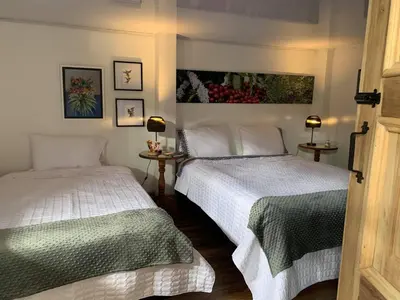 a bedroom with two beds and two lamps and paintings at La Estancia Hotel Boutique in Salamina