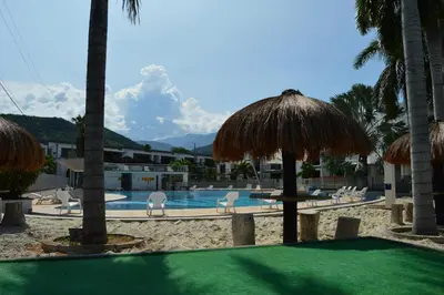 a resort with a swimming pool with chairs and umbrellas at Apartasol Santa Fe de Antioquia in Santa Fe de Antioquia